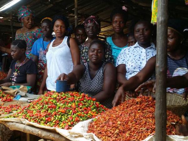 Women in Sierra Leone in front of a market stall with piles of peppers