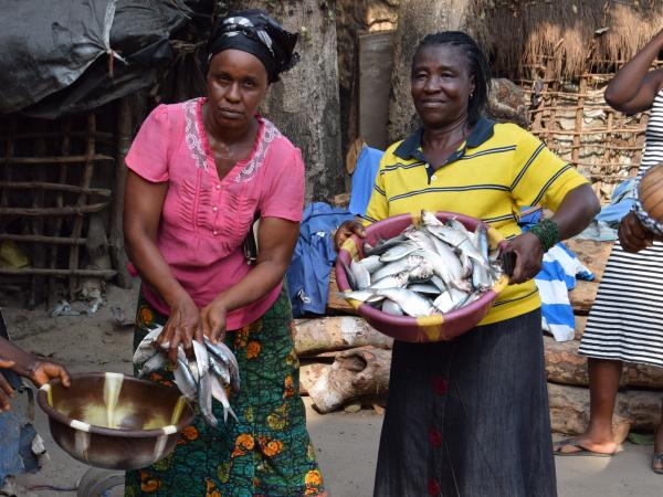 Two GCDF beneficiaries holding baskets of fish