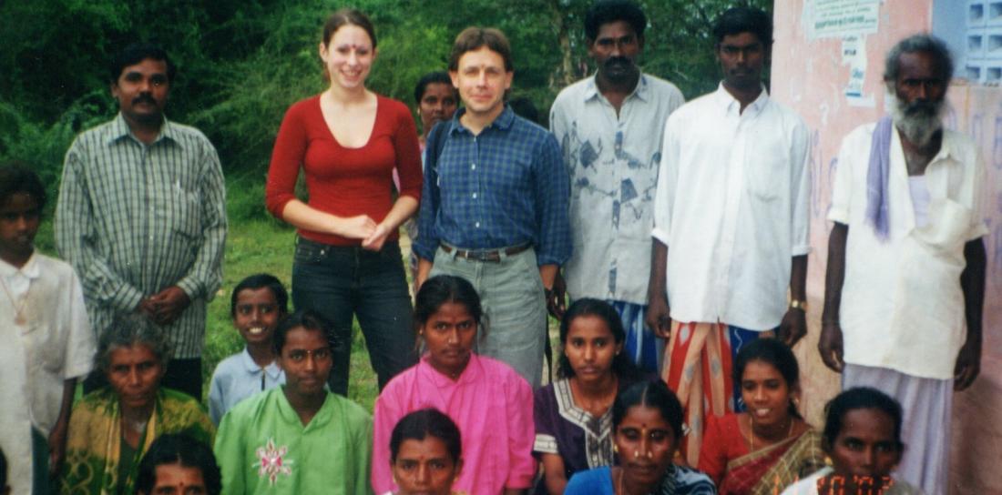 A large group of people stand together outside. 