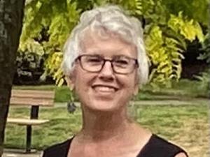 Ruthie stands in front of trees