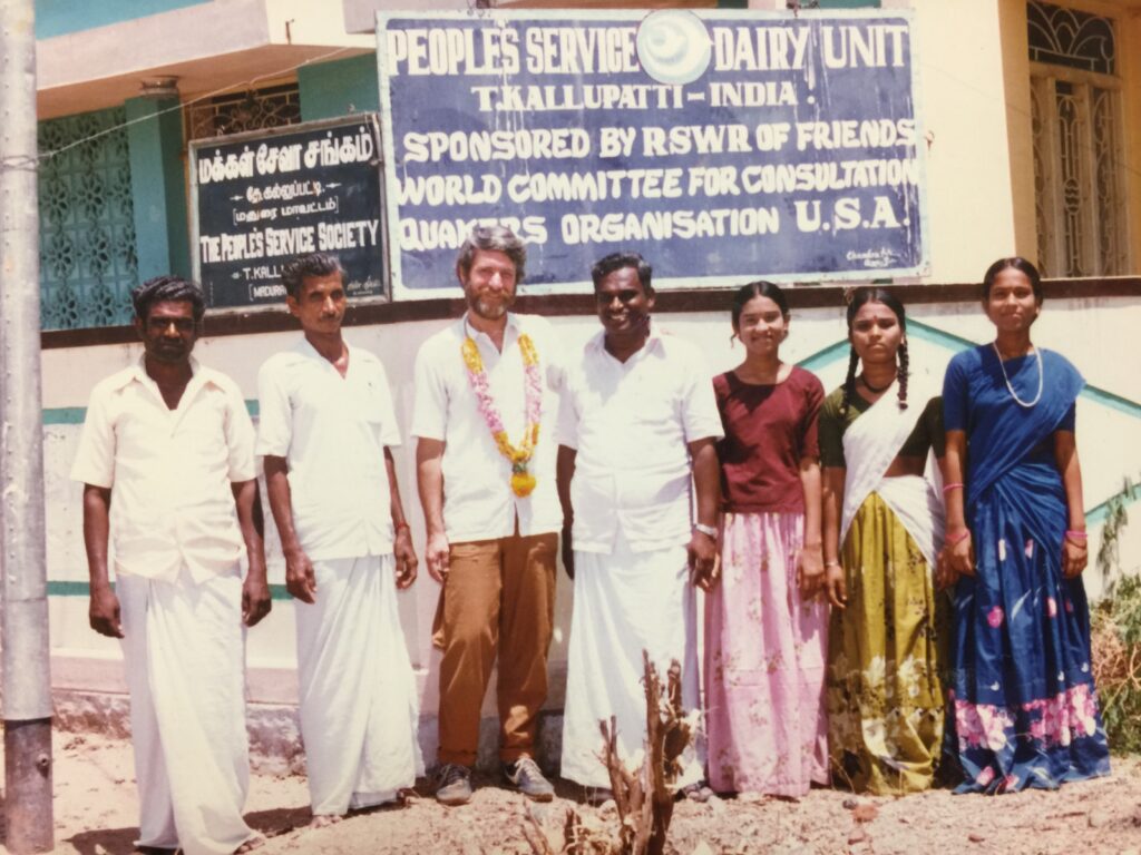 Seven people stand in front of a building with a blue sign for the women's group. 