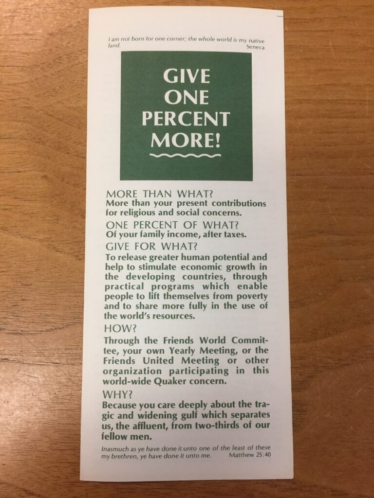 A white pamphlet with green and white text sits on brown, wooden table 