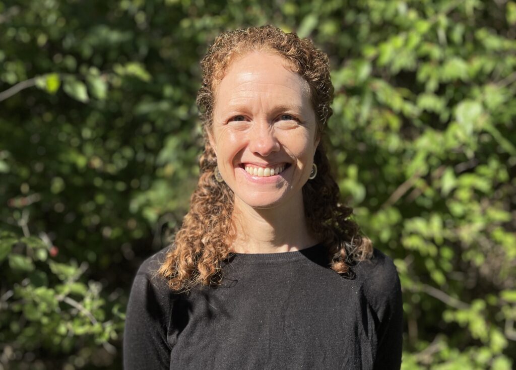 Whitney stands in front of greenery