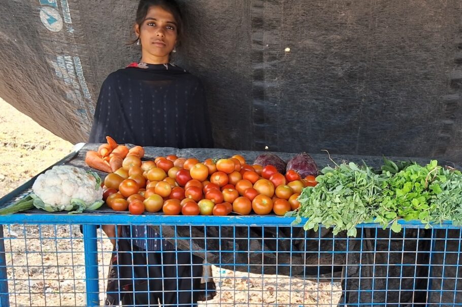 Iswarya stands behind her vegetable stall
