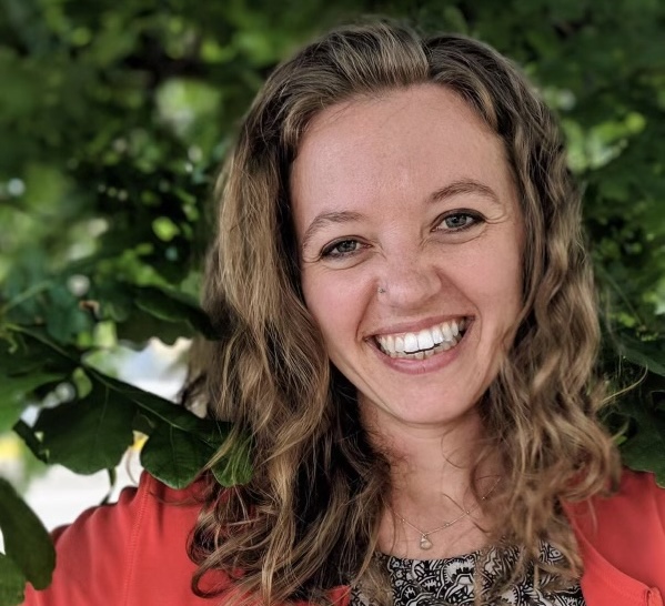 Megan stands in front of greenery