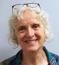 A woman stands in front of a white wall