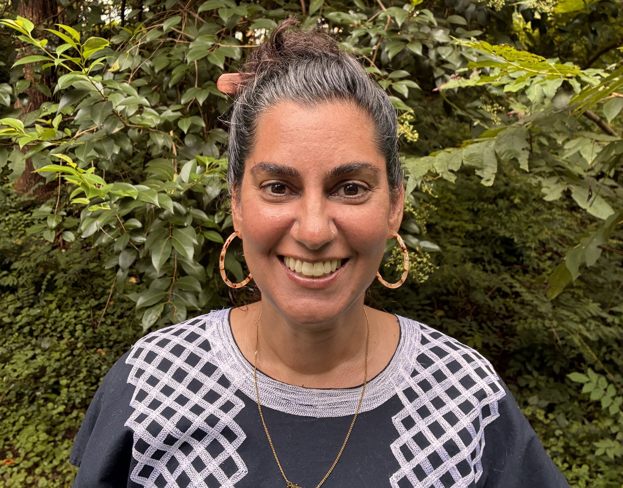 A woman stands in front of a green background