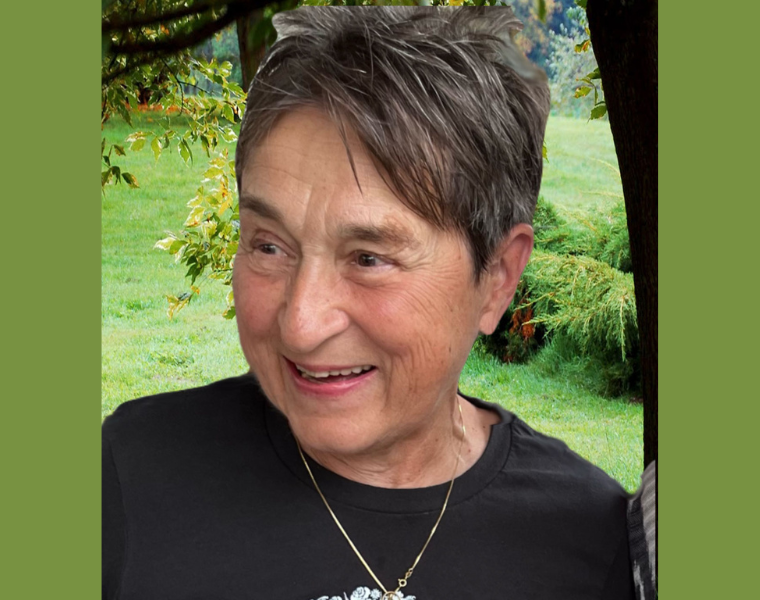 A woman sits in front of some greenery with a tree
