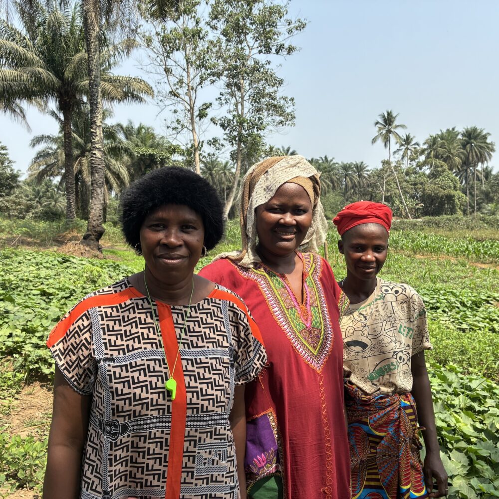 Three women stand in the middle of a green field