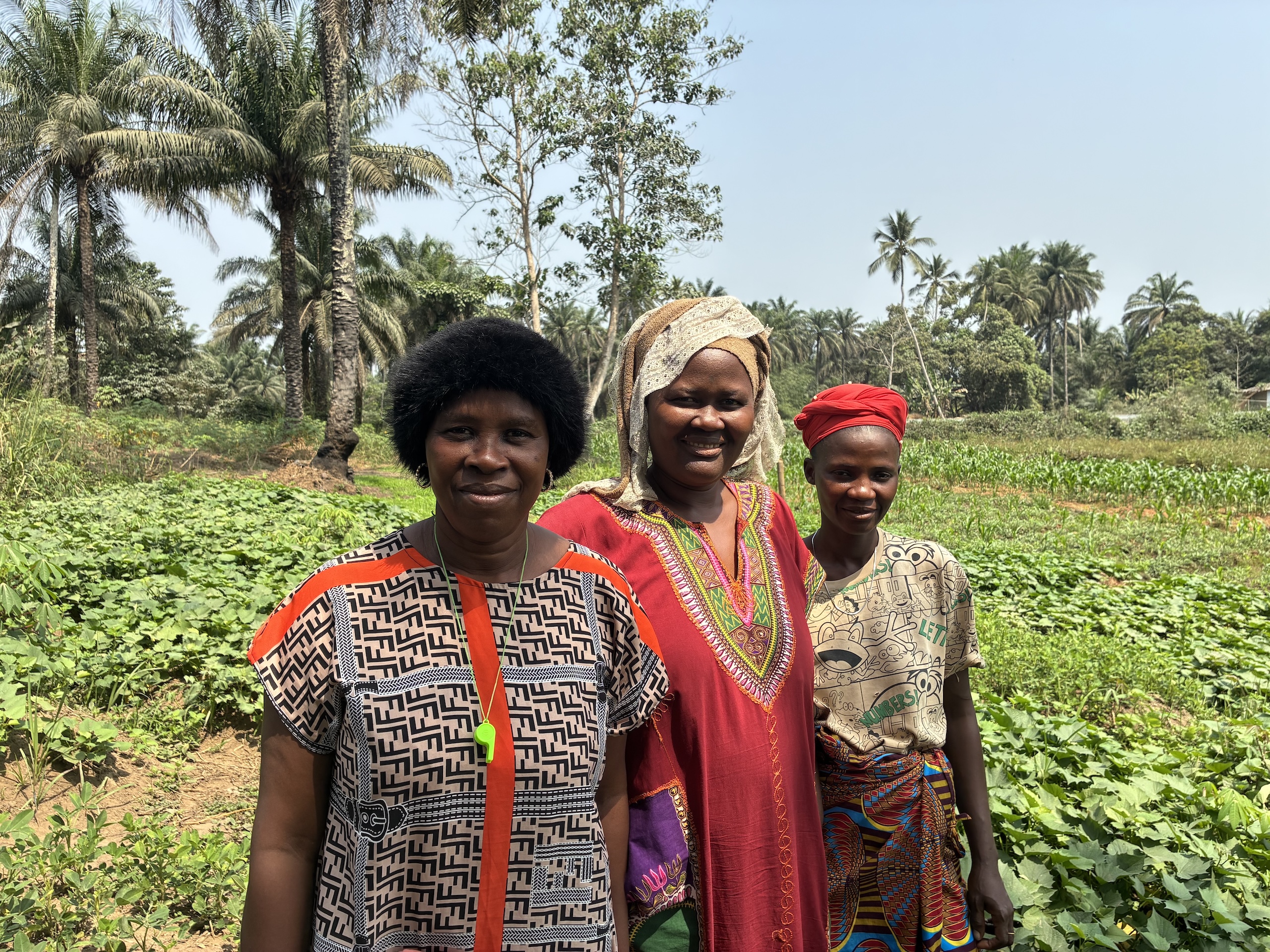 Three women stand in the middle of a green field